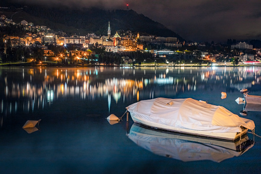 St Moritz illuminated at night and still boats on peaceful lake, Engadine – Switzerland