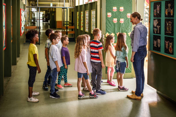 istock Happy female teacher welcoming elementary students in the classroom. 1221540133