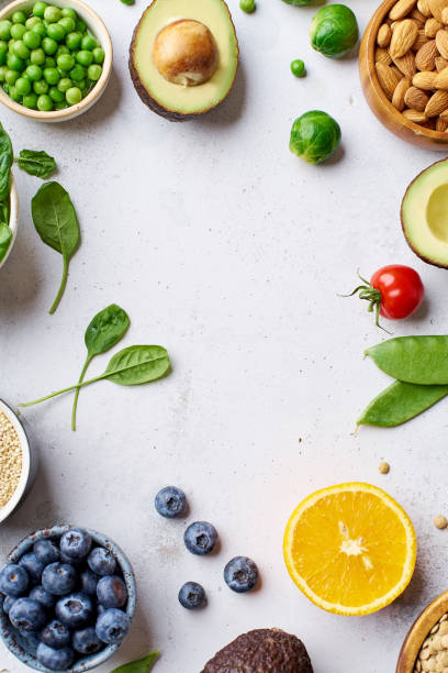 Creative flat lay with healthy vegetarian meal ingredients. Raw food concept. A variety of organic fruits, nuts, berries and vegetables with avocado. Vegan menu frame with copy space stock photo