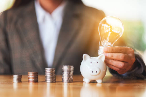 istock A businesswoman putting a light bulb over a piggy bank with coins stack on the table 1221541621