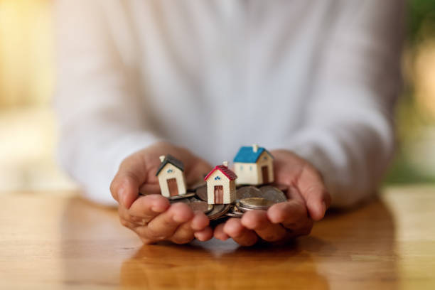 istock a woman's hands holding house models and coins for saving money concept 1221541669