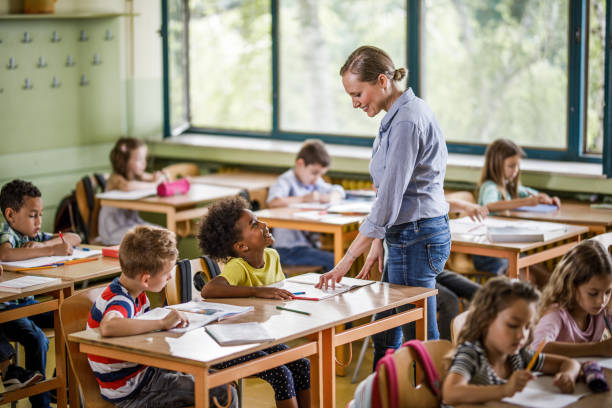istock Happy elementary teacher talking to kids in the classroom. 1221541785