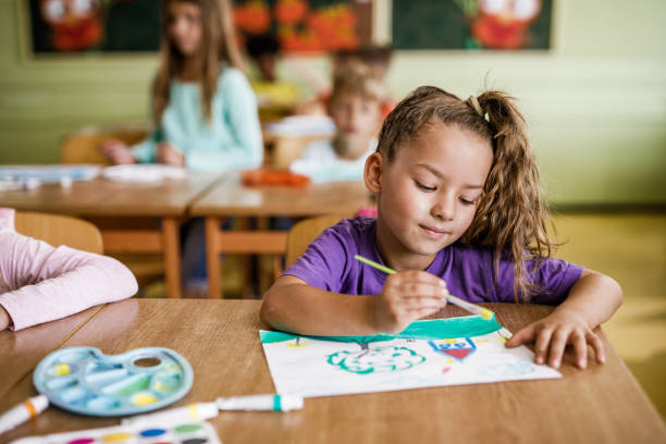 istock Smiling schoolgirl drawing on an art class in elementary school. 1221541806