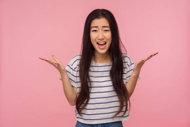 how could you? portrait of displeased girl with long hair in striped t-shirt raising hands in questioning gesture - rudeness manager emotional stress asian ethnicity imagens e fotografias de stock