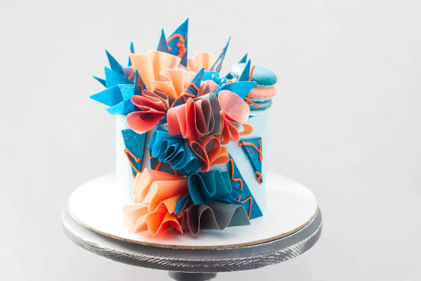 istock Modern blue and orange birthday cake with wafer paper, chocolate and macaroons. Plain background. Copy space. 1221543210