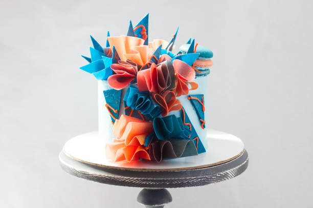 bolo de aniversário azul e laranja moderno com papel wafer, chocolate e macaroons. fundo simples. copiar espaço. - gateaux cake birthday decorating - fotografias e filmes do acervo