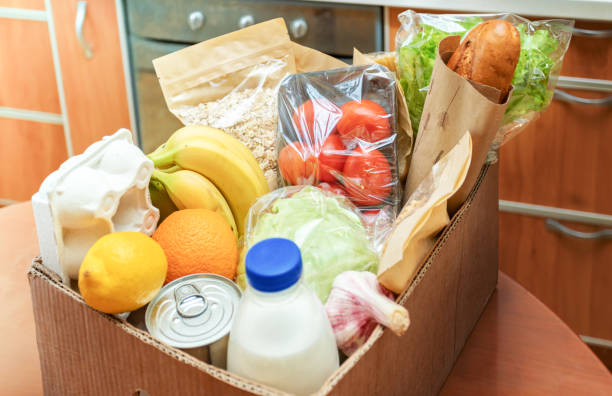 istock Close-up cardboard box with different fresh packed food products on kitchen table. Safe delivery. Selective focus. 1221543311