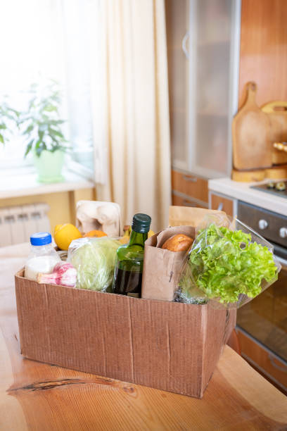 istock Cardboard box with fresh packed food products on wooden table in kitchen interior. Safe delivery. Selective focus. 1221543314