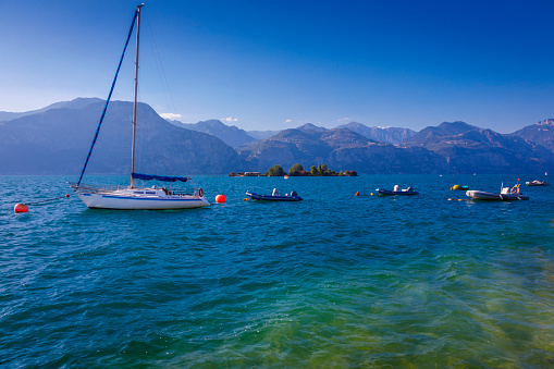 Yachts and sailboats on Lake Garda and Trentino alps near Malcesine, Italy