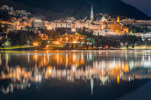 St Moritz illuminated at night and reflection on peaceful lake, Engadine – Switzerland