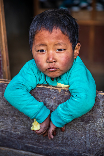 Tibetan little boy sitting inside his father's shop, local village in Upper Mustang. Mustang region is the former Kingdom of Lo and now part of Nepal,  in the north-central part of that country, bordering the People's Republic of China on the Tibetan plateau between the Nepalese provinces of Dolpo and Manang.