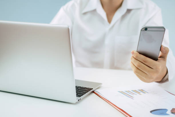 istock hand working with mobile smart phone, laptop computer and business strategy report document on desk at home office, work from home, quarantine, technology, accountant and business financial concept 1221545994