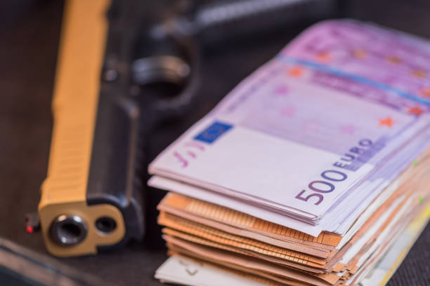 pistola negra y dorada y dinero euros de fondo - gun currency crime mafia fotografías e imágenes de stock