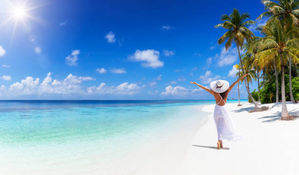 una bandera de concepto de viaje tropical que muestra a una mujer con vestido blanco caminando por una playa paradisíaca - women relaxation tranquil scene elegance fotografías e imágenes de stock