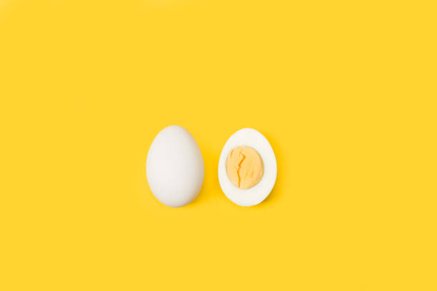 Halved boiled egg and one egg Halved boiled egg and one egg isolated on a yellow background boiled egg photos stock pictures, royalty-free photos & images
