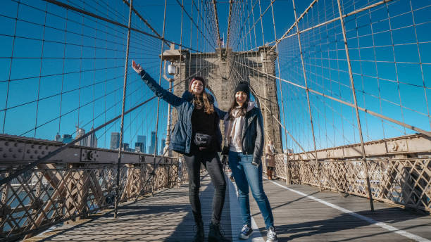 due ragazze camminano sul famoso ponte di brooklyn a new york - brooklyn bridge taxi new york city brooklyn foto e immagini stock