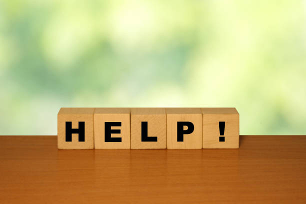 istock HELP message word on a wooden desk on cube blocks with a green nature background 1221552131