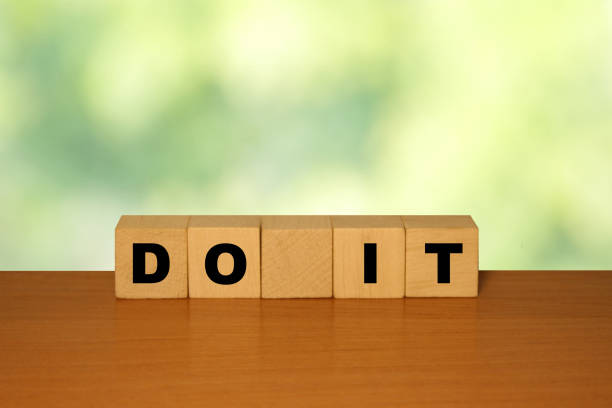 istock DO IT message word on a wooden desk on cube blocks with a green nature background 1221552149