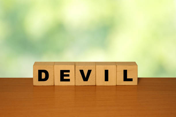 istock DEVIL message word on a wooden desk on cube blocks with a green nature background 1221552184