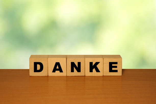 istock DANKE message word on a wooden desk on cube blocks with a green nature background 1221552308