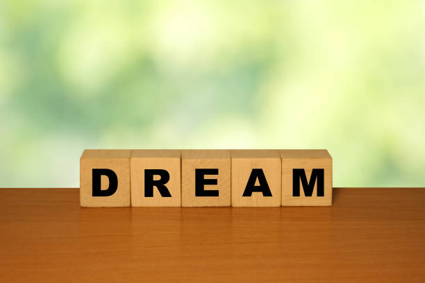 istock DREAM message word on a wooden desk on cube blocks with a green nature background 1221552360