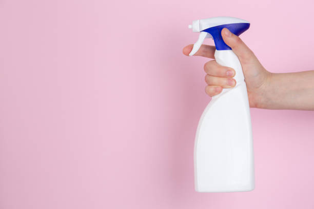 istock A woman hand squeezing a spray bottle on a pink background 1221553417