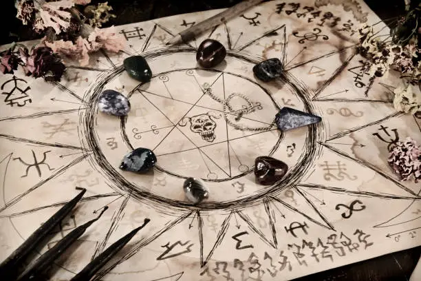 Drawing with magic spells, minerals and black candles on witch table. Wicca, esoteric and occult background with vintage magic objects for mystic rituals. Halloween and gothic concept