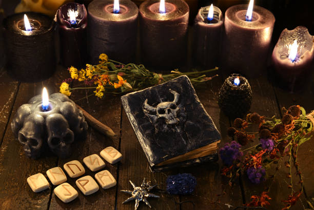 istock Black candles, runes, old witch book and herbs on wooden table. 1221553635