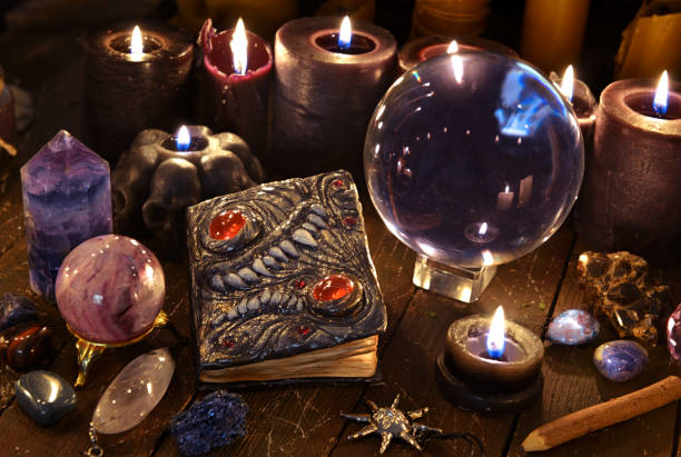 istock Crystal ball, magic book and burning black candles on witch table. 1221553723