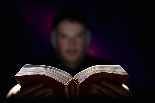 Blurred man on dark background holding a book in his hands religious concept