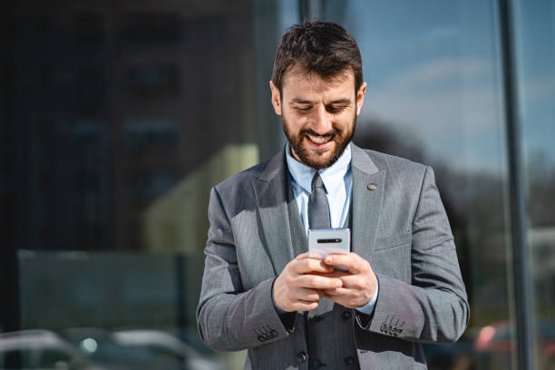 istock Smiling businessman using cellphone outdoors 1221555377