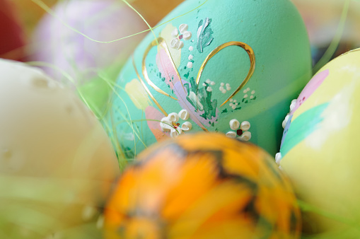 Easter eggs painted in pastel colors on a white background with copy space and cute spring flowers, Happy Easter Holiday concept with space for text. Yellow pink and blue bright colors