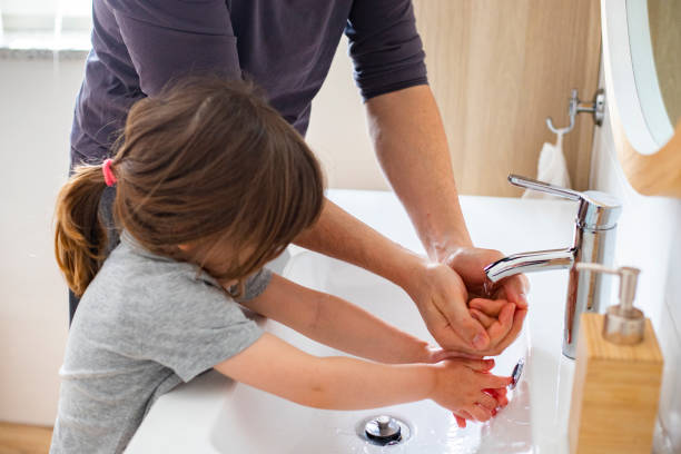 young father washing hands with little child girl during pandemic. stock photo
