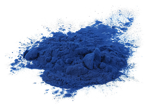 A heap of blue spirulina powder, isolated on white background