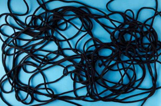 top view of entangled black rope on the blue background - nylon strings imagens e fotografias de stock