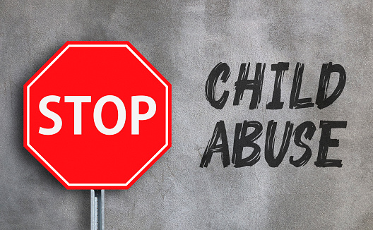 Stop Child Abuse with stop sign on wall background.