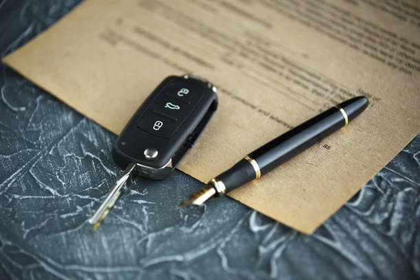 Black car key and money on a signed contract of car sale. Black car key and money on a signed contract of car sale. Focus on a key. car keys table stock pictures, royalty-free photos & images