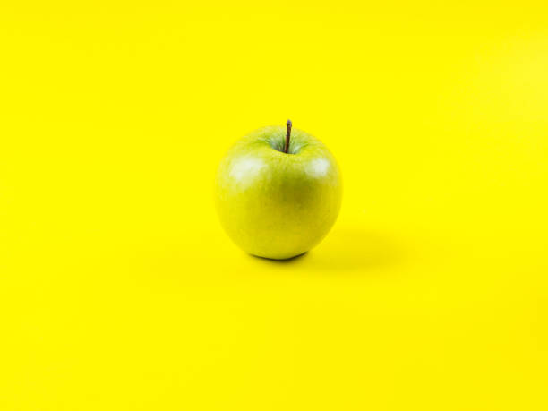 istock Shiny green apple on bold yellow background 1221578063