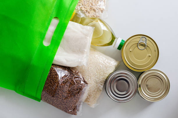 shelf-stable products packaged in a green bag. canned food and cereals - food donation box groceries canned food imagens e fotografias de stock