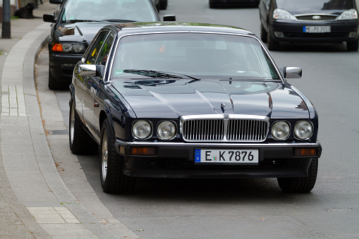 Black vintage Jaguar limousine parked in Essen Werden seen in street Brueckstrasse. Some traffic is ruling in street