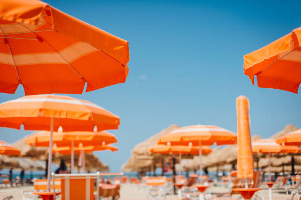 Orange umbrellas on the beach against the blue sky. Bottom view. Summer travel