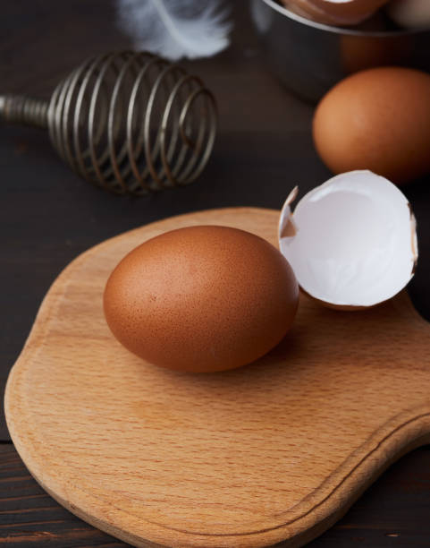 istock brown whole chicken eggs on a wooden board, behind a whisk for w 1221585151