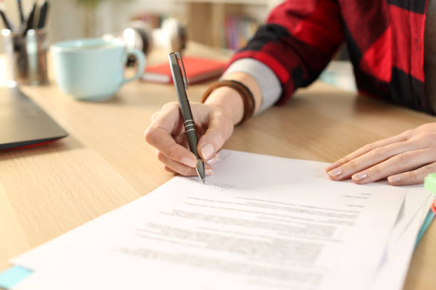 istock Student hands signing contract sitting at home 1221585481