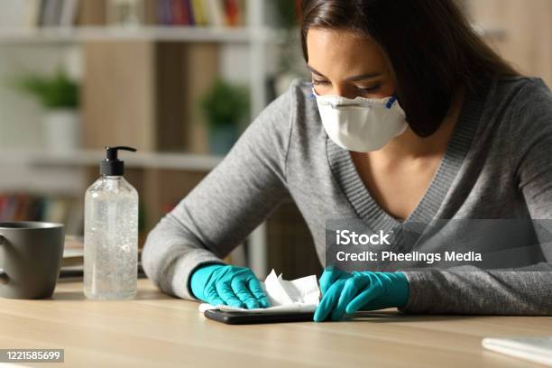 Woman Disinfecting Phone From Coronavirus At Night At Home Stock Photo - Download Image Now