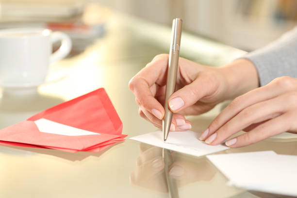 Woman hand writing greeting card at home Close up of woman hand writing greeting thank you card sitting on a desk at home writing a letter stock pictures, royalty-free photos & images