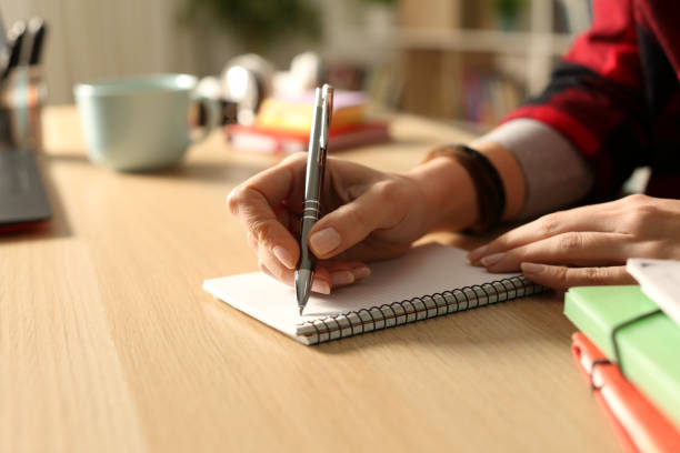 Student girl hands writing on notebook at night