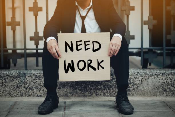 istock An unemployed man holding a paper sign writing a message saying he needs a job 1221591425