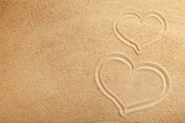 istock Drawing hearts in the sand. Summer concept 1221591834