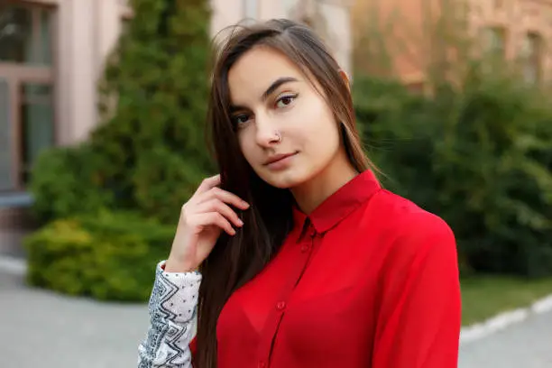Charming young woman with a magnificent brunette hair, big eyes, gorgeous red lipstick and stylish look. Attractive young lady is rushing in the city-center, she turns to camera and smiles.