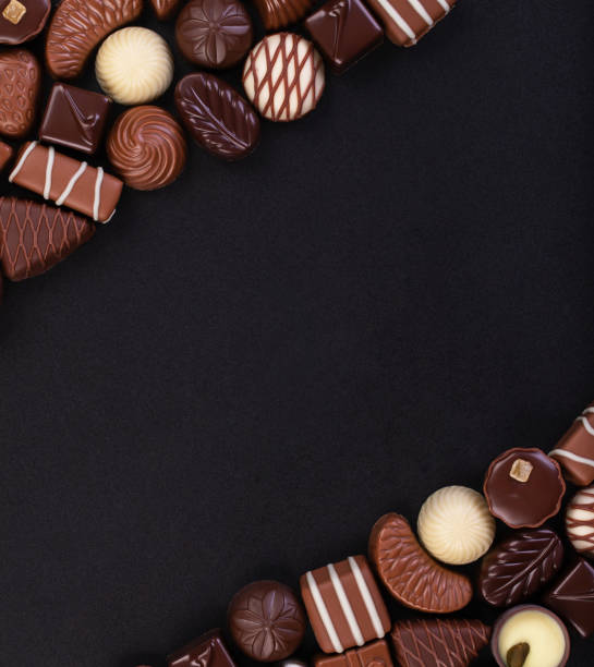 istock assorted candy of white and dark chocolate on black table background with empty space 1221594286